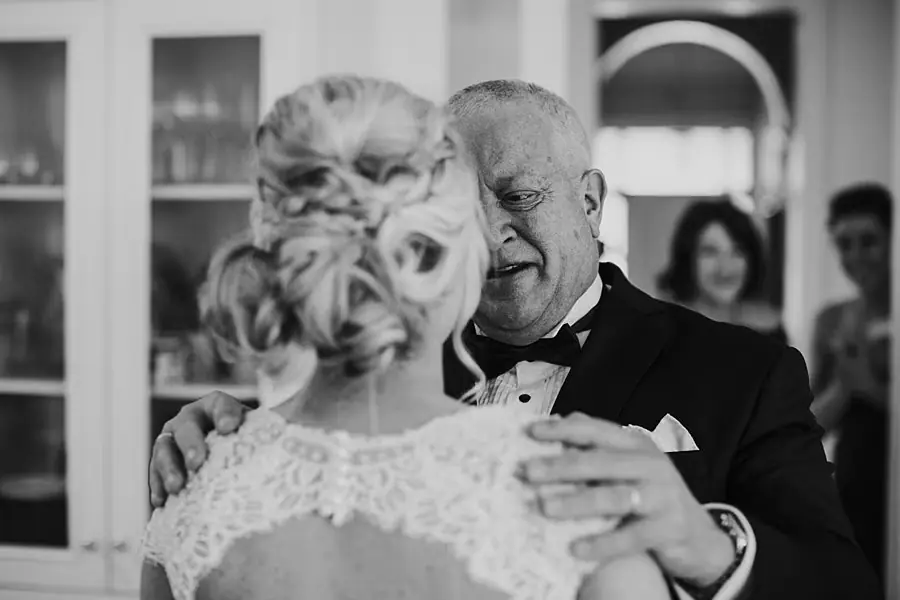 Black-and-white close-up of the bride and a suited man embracing.