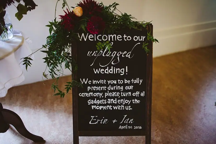 Floral sign asking guests to switch off devices for an unplugged wedding ceremony.