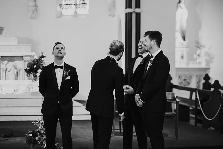 Black-and-white photograph of suited men looking upward inside a church.
