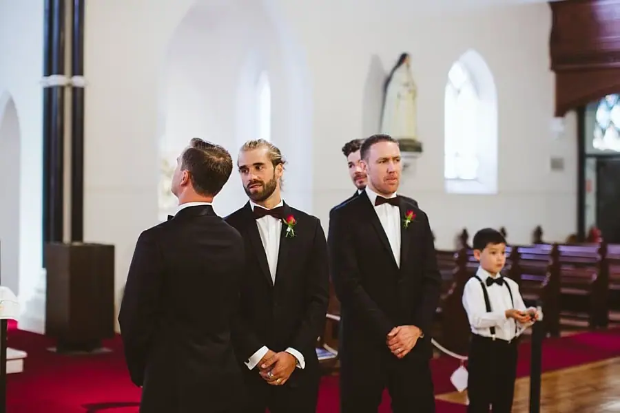 Suited men and a boy standing near the front of a church.