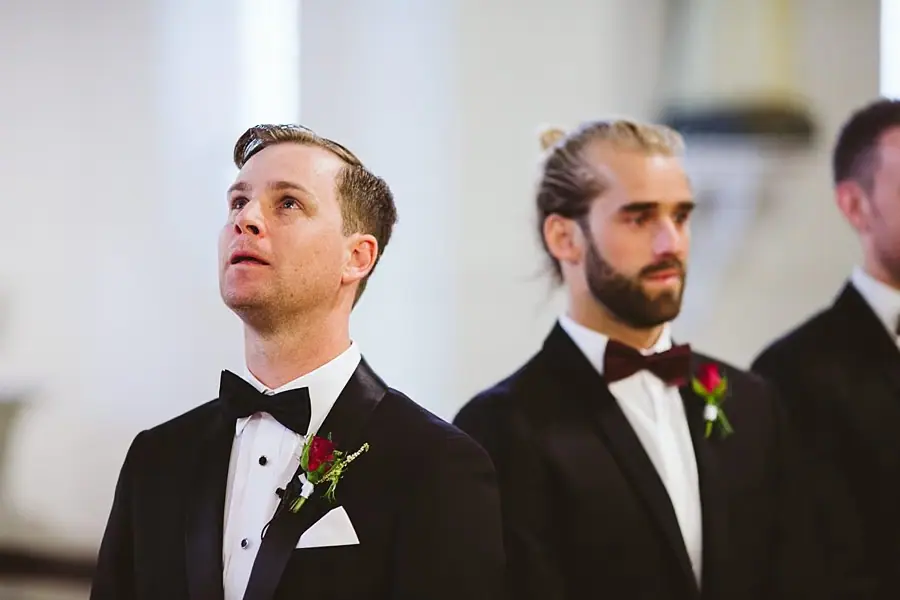 Close-up of the groom and a suited companion inside the church.