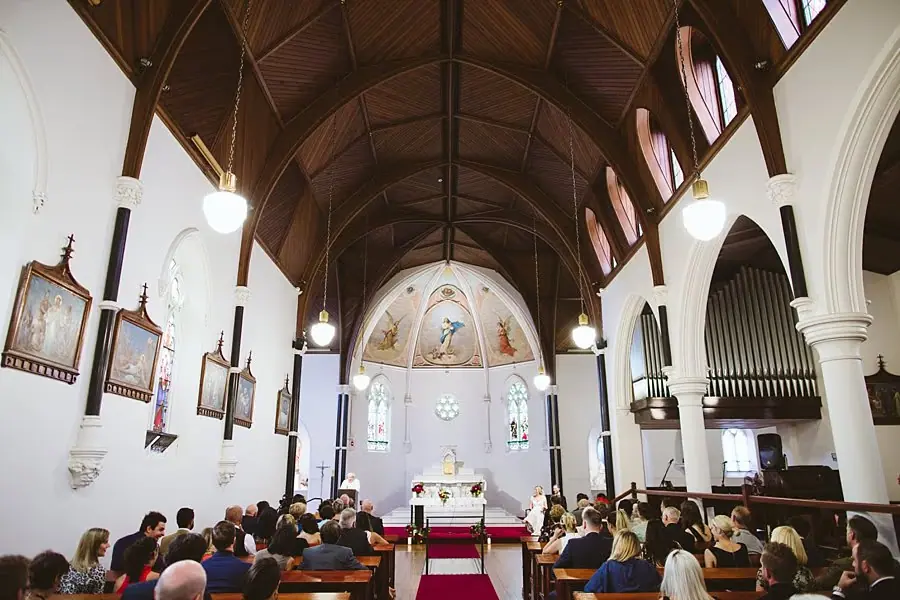Wide view of guests seated beneath the timber roof of a church.