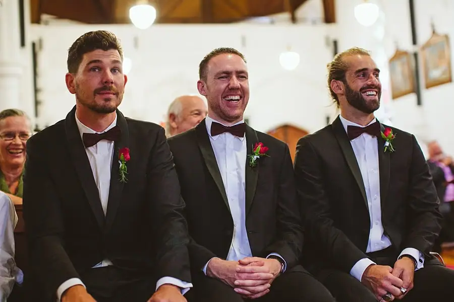 Three suited men smiling while seated inside the church.