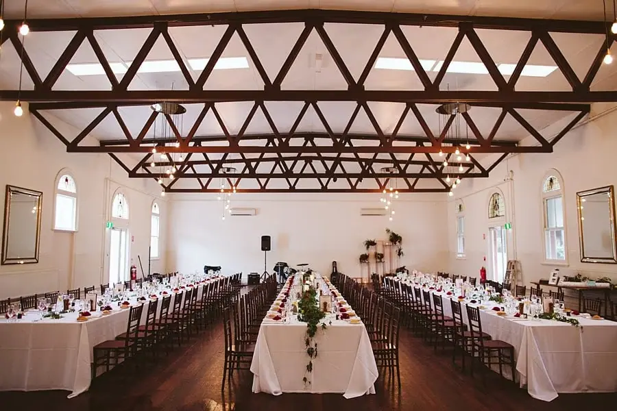 Long reception tables beneath exposed timber roof trusses.