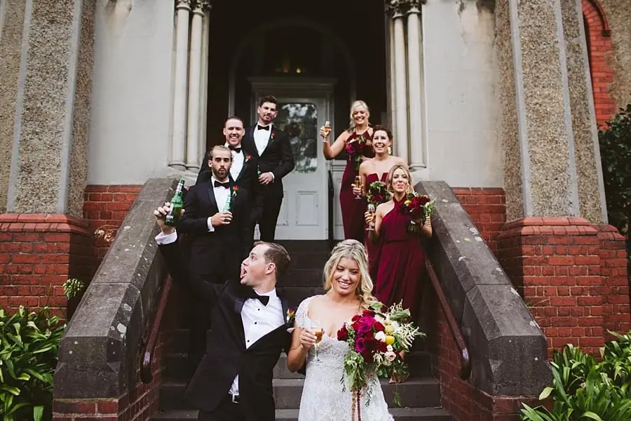 Wedding party arranged on steps outside an ornate building entrance.