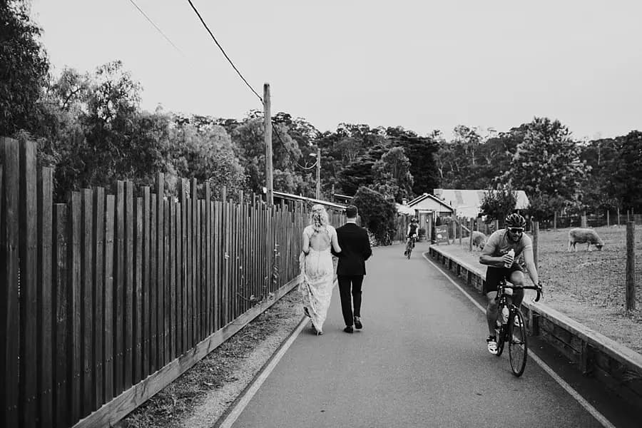 Black-and-white photograph of the couple walking along a path beside a cyclist.