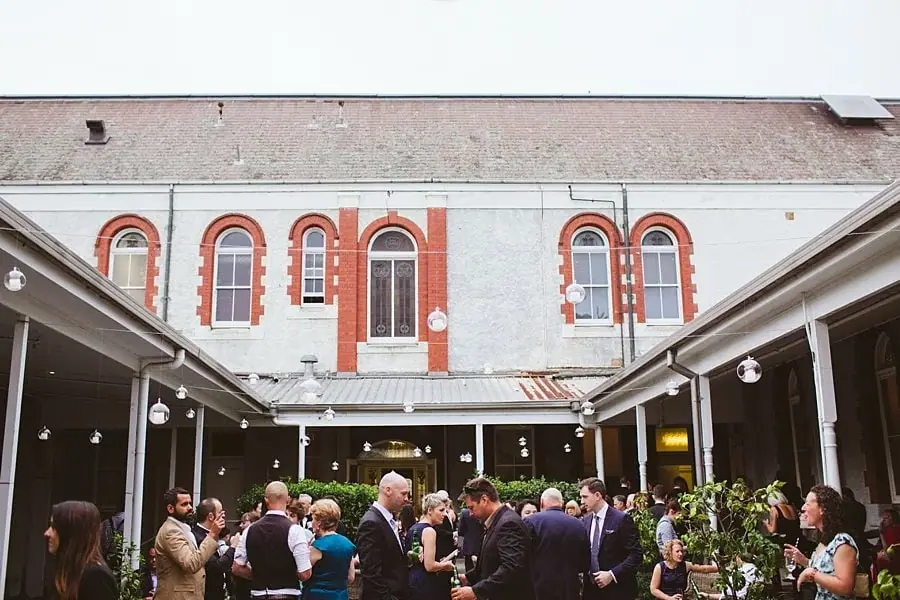 Guests mingling in a courtyard beneath a tall brick-trimmed building.