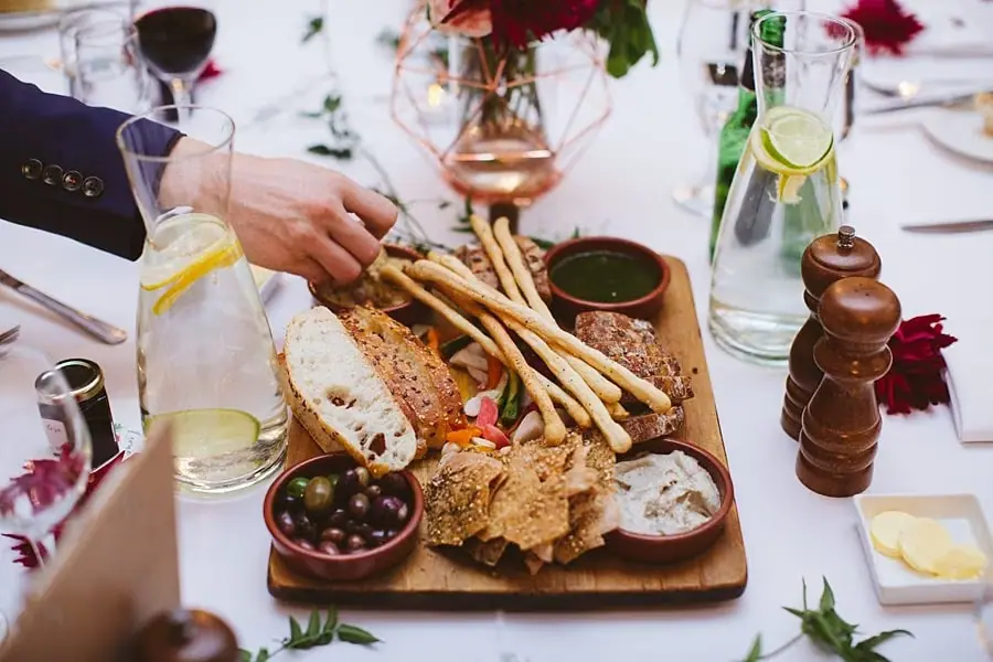 Close-up of a shared platter of bread, crackers and cheeses on a reception table.