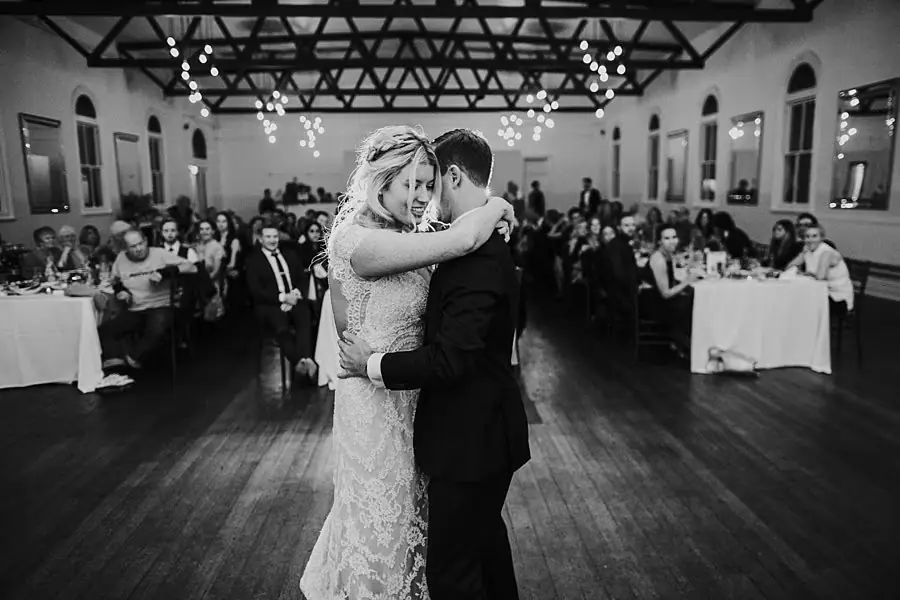 Black-and-white photograph of the bride and groom kissing on the dance floor.