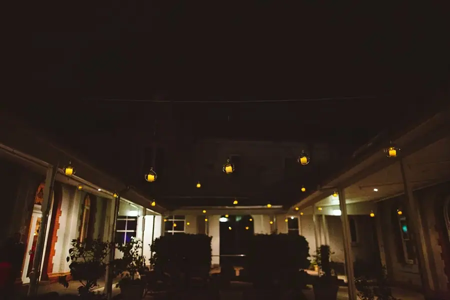 Dark courtyard at night illuminated by hanging lights.