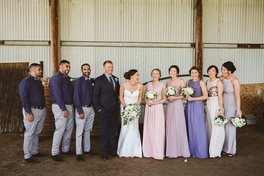 Couple and wedding party posing beside the barn