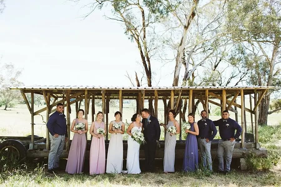 Wedding party beneath a timber shelter beside the paddock