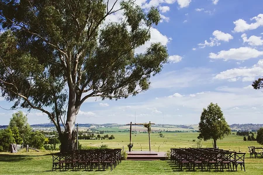 Outdoor ceremony chairs facing a timber wedding arbour