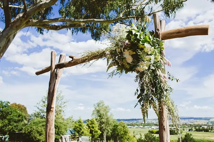 Flowers and greenery decorating the timber ceremony arbour