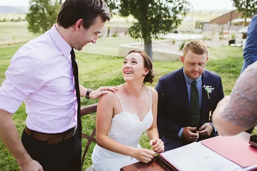 Couple laughing with the celebrant while signing the register