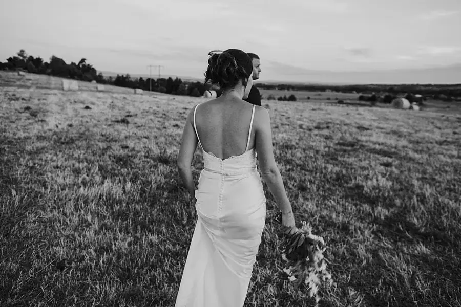 Black-and-white portrait of the bride looking across the paddock