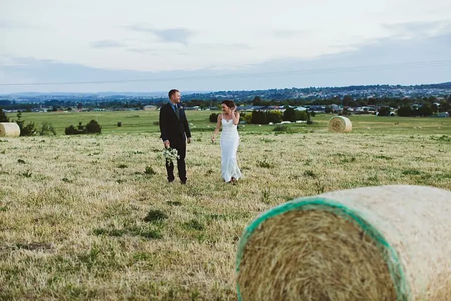 Couple walking through a paddock beside a hay bale