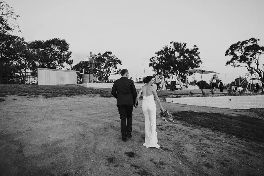 Black-and-white photograph of the couple walking back toward the reception