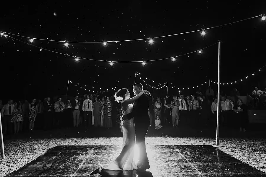 Black-and-white photograph of the couple dancing beneath festoon lights