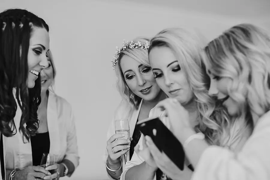 Black-and-white photograph of women gathering around a phone.