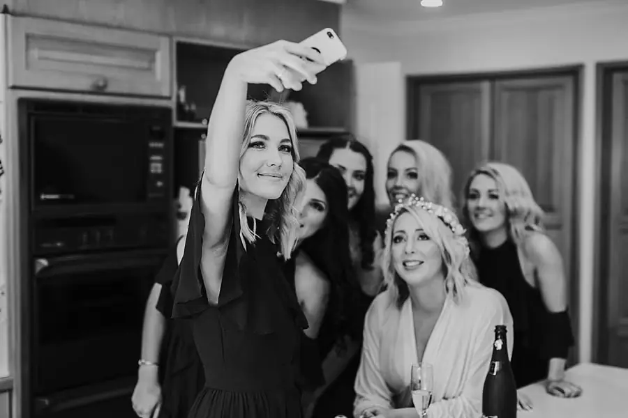 Black-and-white photograph of women smiling for a phone selfie.