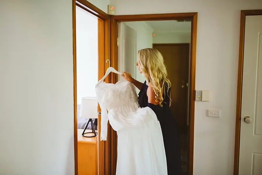 Woman holding a white wedding dress on a hanger.
