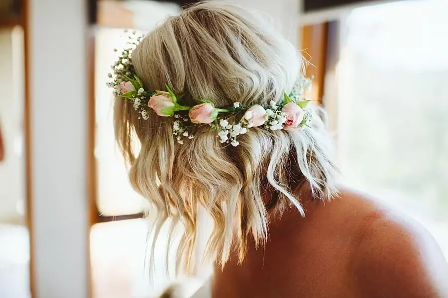 Close-up of pale pink flowers woven into the bride's hair.