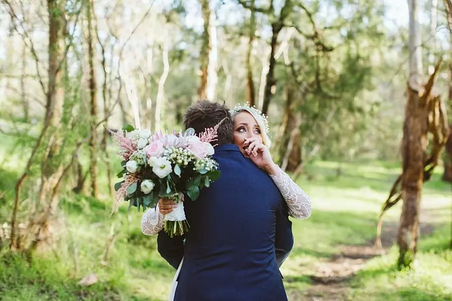Bride embracing the groom and looking upward through the trees.