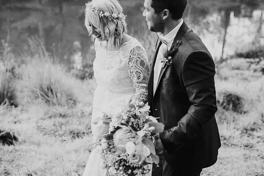 Black-and-white photograph of the bride and groom standing together with a bouquet.
