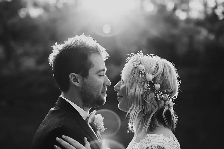 Black-and-white close-up of the bride and groom facing each other in sunlight.