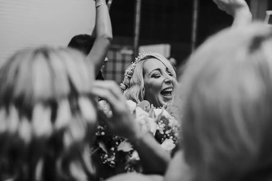 Black-and-white photograph of a woman laughing among celebrating guests.
