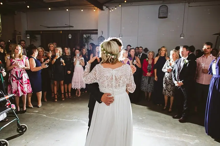 Bride and groom dancing while guests watch around them.