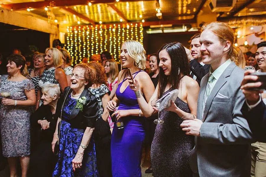 Guests smiling and laughing together beneath warm reception lights.