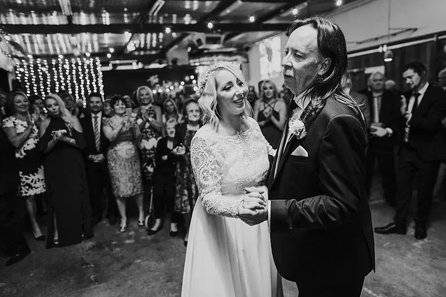 Black-and-white photograph of the bride dancing with a suited man.