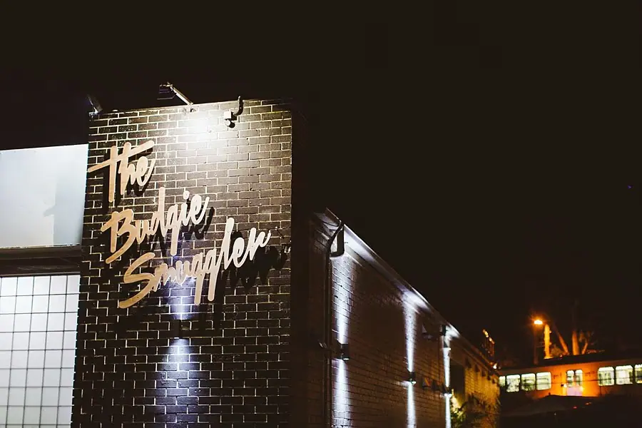 Illuminated painted lettering on the corner of a brick building at night.