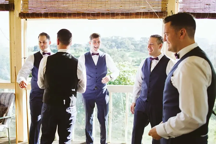 Men in white shirts and dark waistcoats gathering beside a balcony doorway.