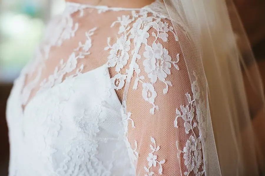 Close-up of lace sleeves and floral detailing on the bride's wedding dress.