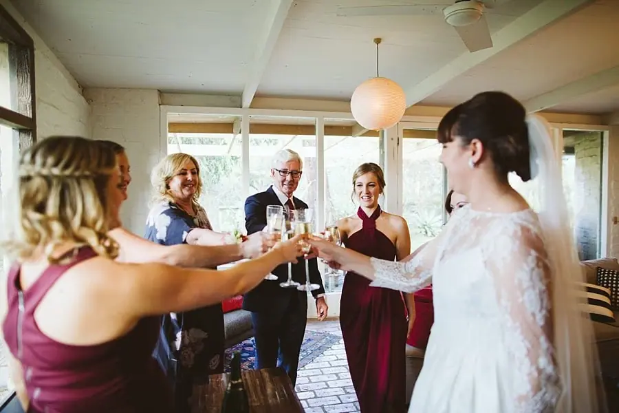 Bride and guests raising their glasses together indoors.