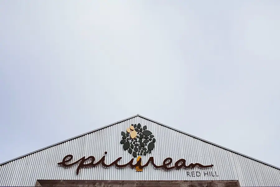 Restaurant roof with a large Epicurean Red Hill sign beneath an overcast sky.