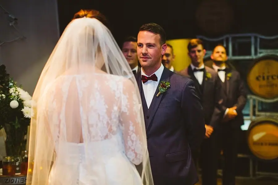 Groom looking at the veiled bride during the indoor ceremony.