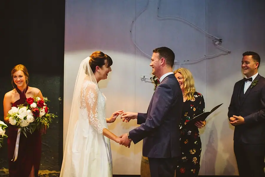Bride and groom holding hands during their wedding ceremony.