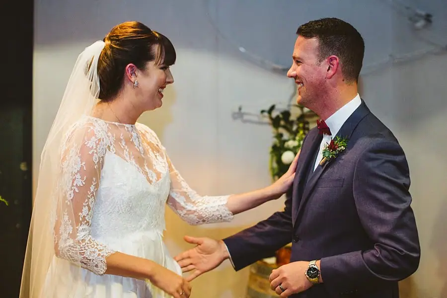 Bride and groom smiling at each other after their ceremony kiss.