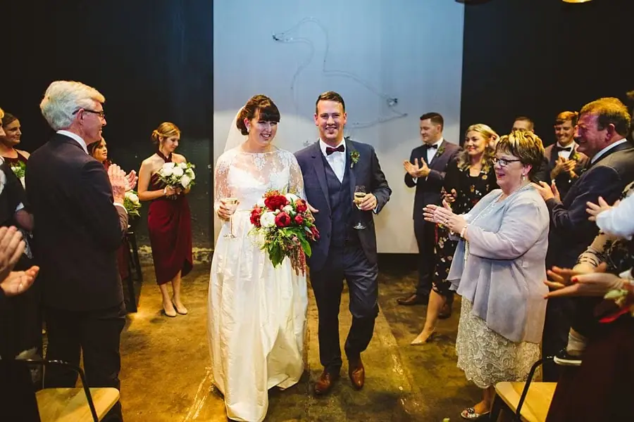 Newlyweds walking between applauding guests after the indoor ceremony.