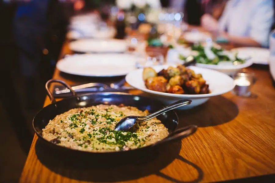 Shared reception dishes arranged along a wooden dining table.