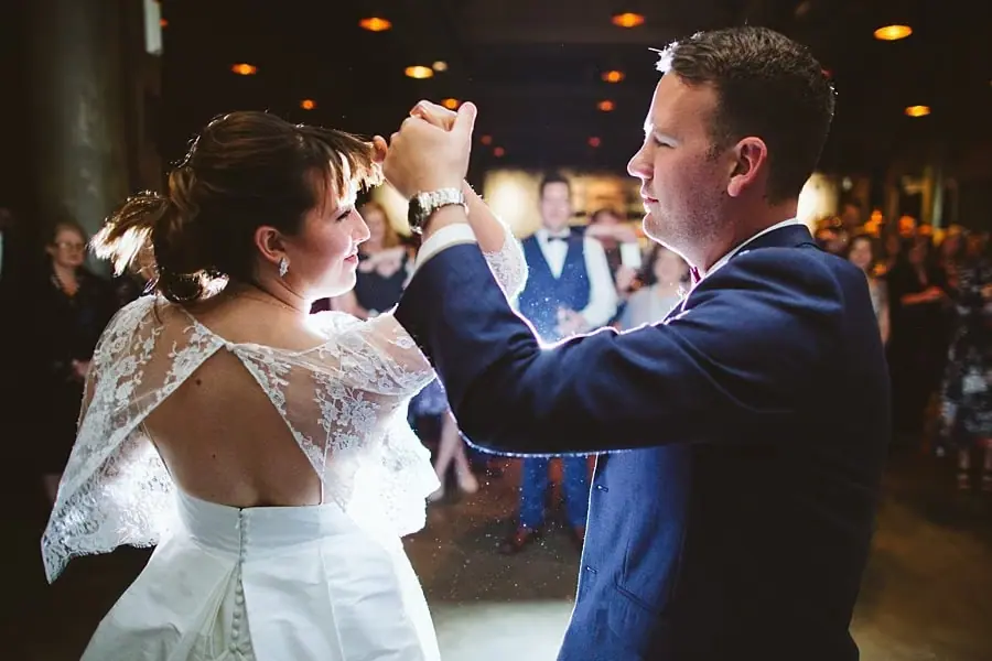 Bride and groom holding their joined hands up while dancing together.