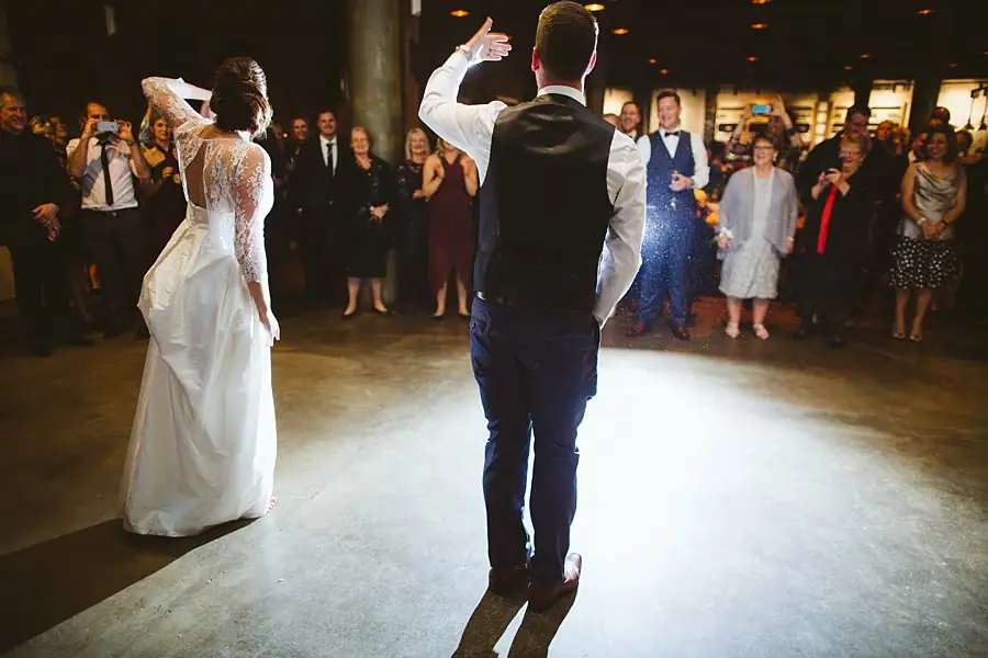 Bride and groom dancing while guests form a circle around them.