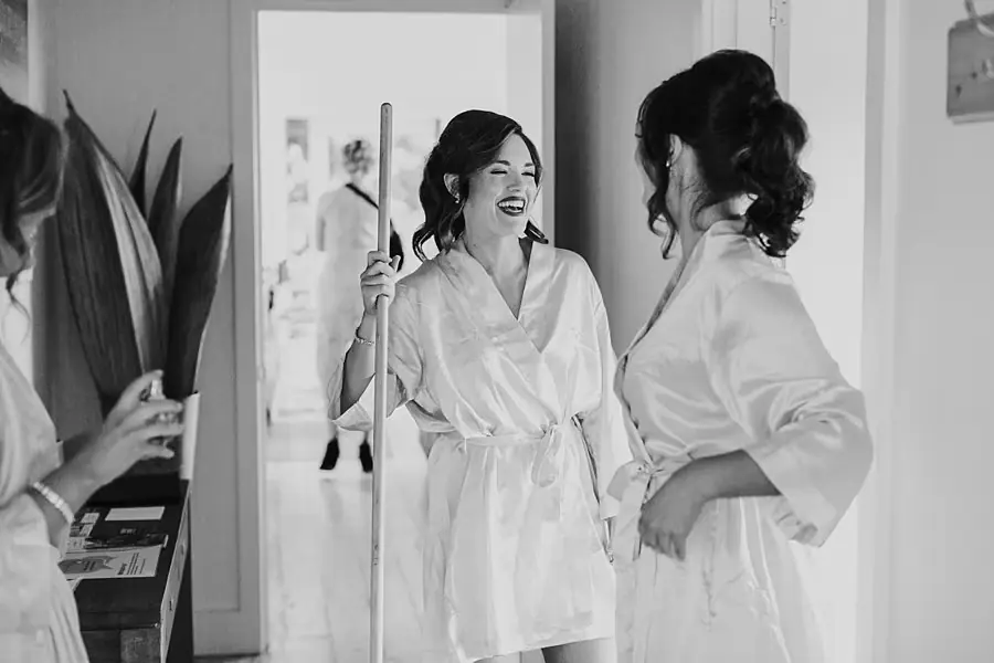 Black-and-white photograph of two women in white robes smiling at each other.