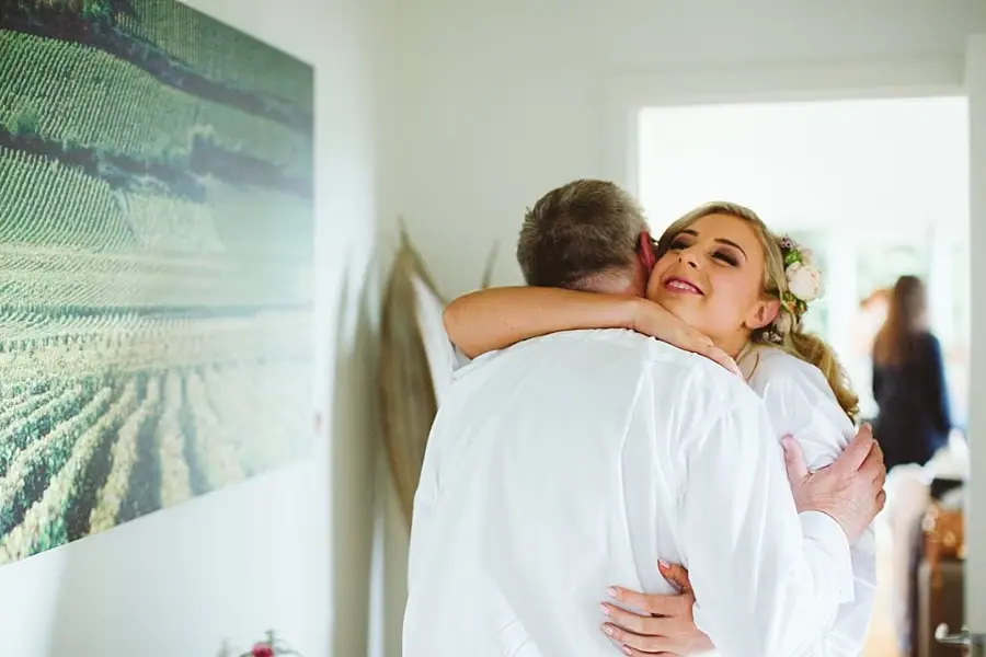 Bride in a white robe embracing another person before the wedding.