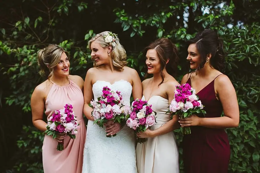 Bride and three bridesmaids standing together in the garden with pink and white bouquets.