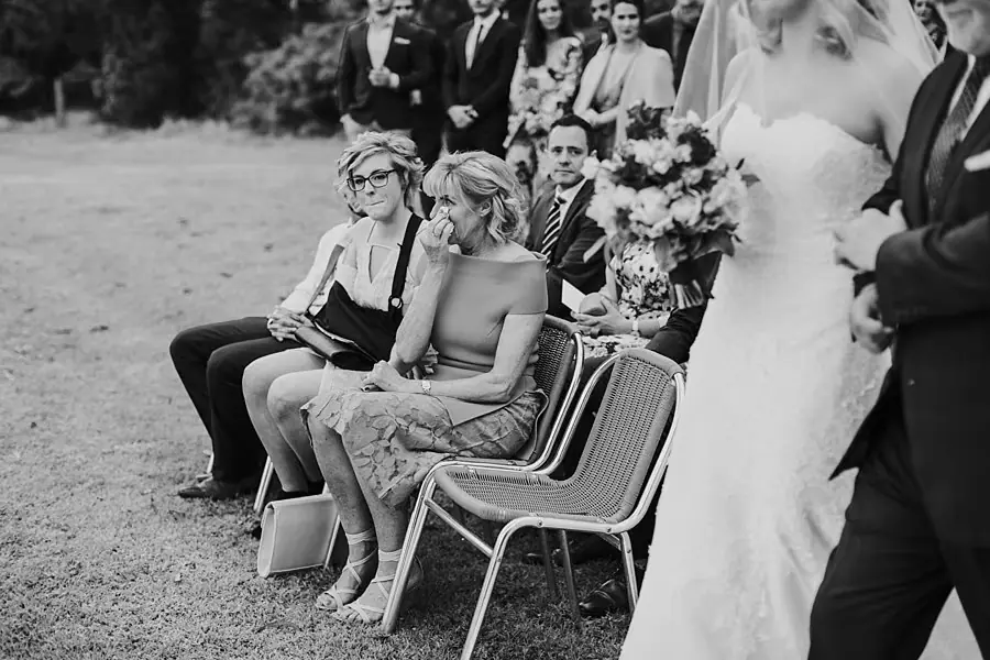 Black-and-white photograph of wedding guests seated beside the ceremony aisle.